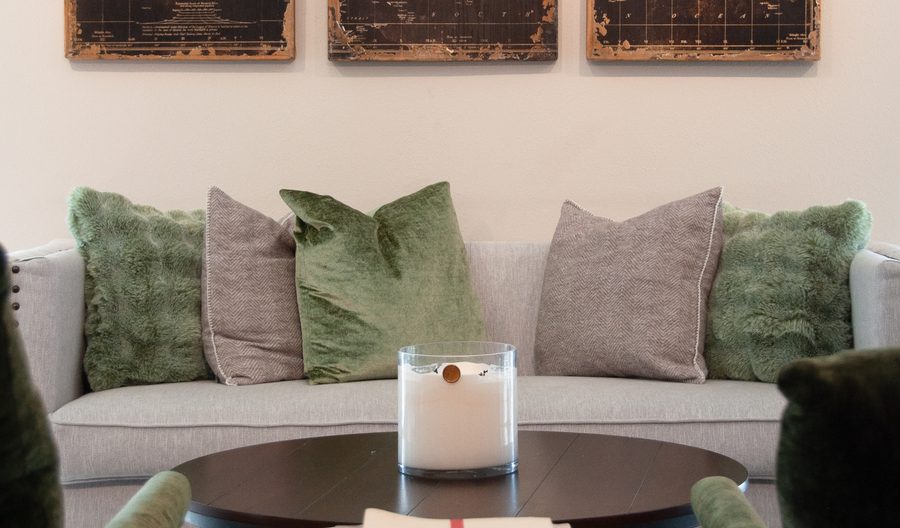 A warm consult space with a couch, green and grey pillows, and vintage world map artwork
